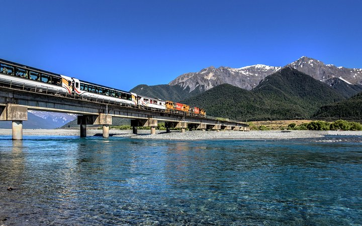 Journey through stunning landscapes as the TranzAlpine Train glides alongside the Waimakariri River revealing majestic Southern Alps and lush beech forests perfect for unforgettable travel memories.